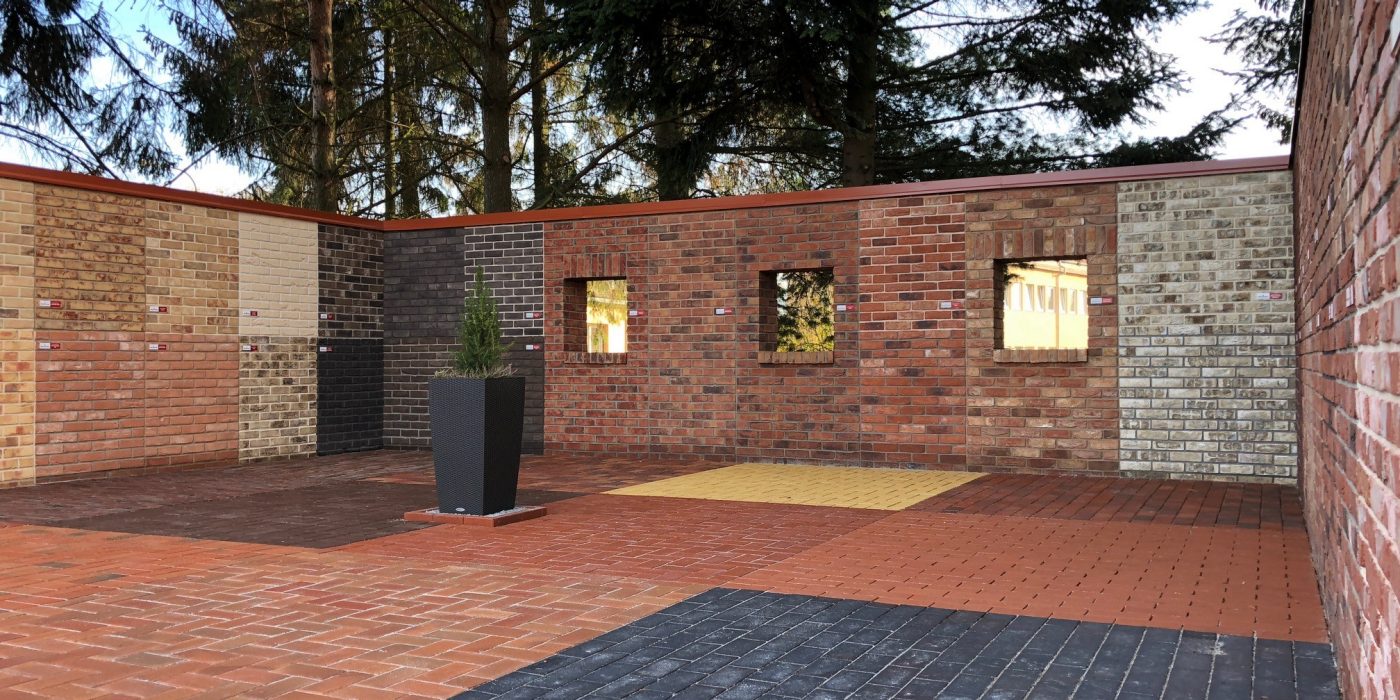 Muž v pracovním oblečení a helmě stojící ve výrobním závodě