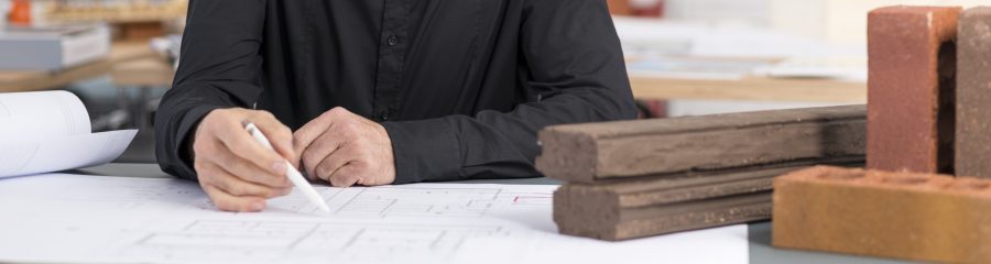 Senior architect sitting at office desk with blueprint and a selection of Wienerberger facing bricks