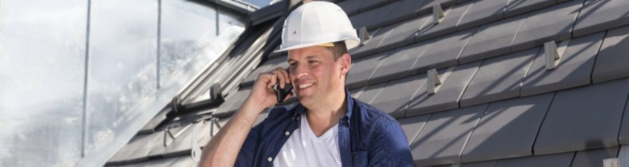 Roofer with telephone sitting on roof laid with Actua roof tiles