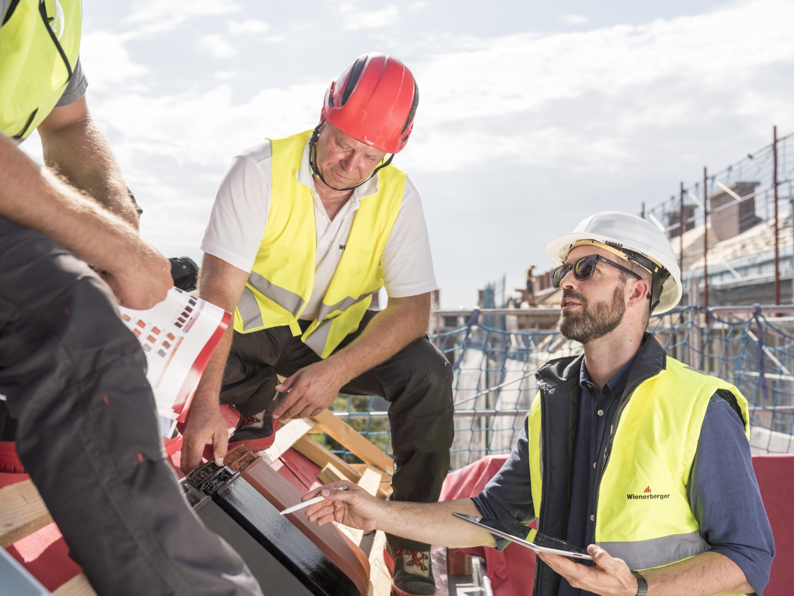 Product manager explaining product advantages to urban roofers wearing safety jackets and hard hats