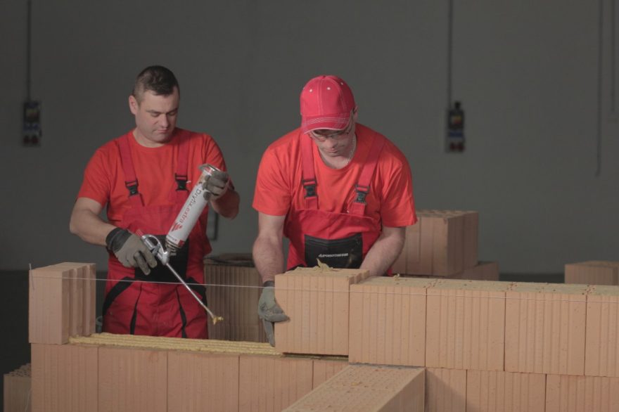 Two bricklayers laying Porotherm T Profi bricks with Porotherm Dryfix