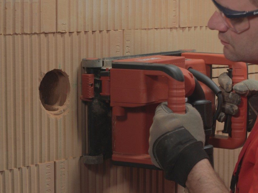 A bricklayer cutting a groove into a brick wall